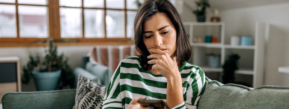 Nachdenkliche Frau informiert sich per Handy in der bonify-App